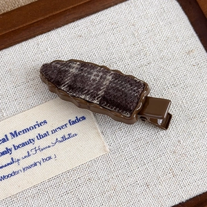Detailed macro view of the retro brown resin hair clip with textured tweed fabric inlay