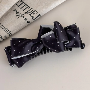 Dettaglio di un fermaglio per capelli in raso nero a pois con un fiocco raffinato