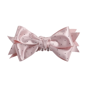 Dettaglio del fermaglio a fiocco in raso rosa con pois neri su sfondo bianco