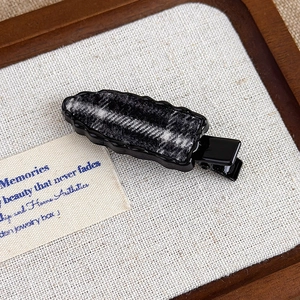 Close-up of black alloy duckbill hair clip featuring grey checkered wool fabric inlay