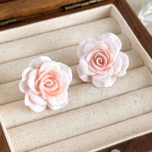 Détail des boucles d'oreilles roses en dégradé présentées dans un écrin à bijoux en bois