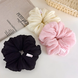Detailed view of cream ruffled scrunchies in black, beige and pink with handmade labels