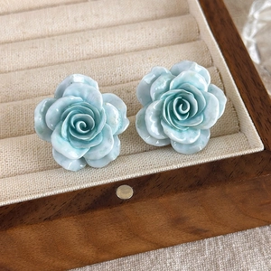 Gros plan de boucles d'oreilles roses bleu clair avec pétales dans un écrin en velours