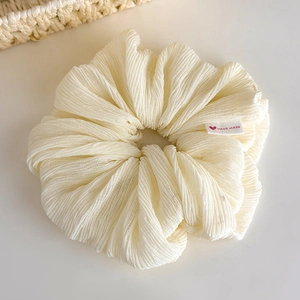 Detail showing high-elastic cream scrunchie with handmade heart label and vertical texture