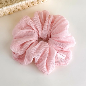 Detail view of pink pleated scrunchie fabric texture with a handmade heart label