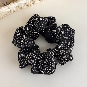 Makroaufnahme von elegantem schwarzem Satin-Scrunchie mit funkelnden klaren Strasssteinen