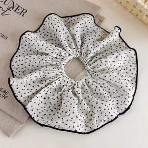 Détail d'un grand chouchou à pois avec bords ondulés noirs sur tissu en coton