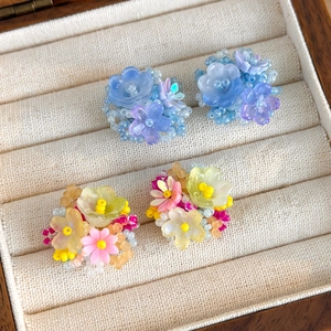Détails de boucles d'oreilles hortensia en perles pastel faites main dans une boîte en bois