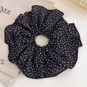 Vue détaillée du grand chouchou en maille noire à pois blancs sur tissu en lin naturel
