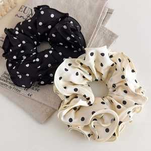 Detail of black and beige polka dot satin scrunchies with pleated edges on linen cloth