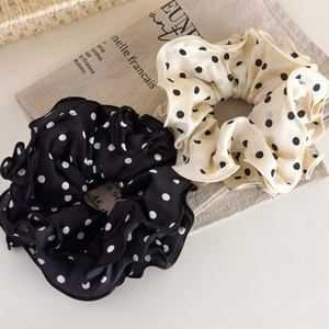 Close-up of black and white polka dot satin scrunchies with elegant ruffled edges
