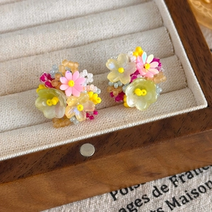 Détail de boucles d'oreilles florales 3D avec perles de résine sur boîte en bois