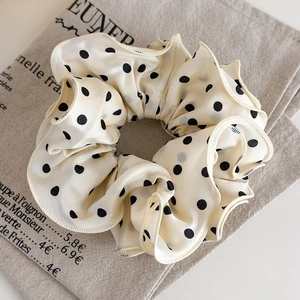 Close-up of beige polka dot scrunchie with layered ruffled edges and satin fabric texture