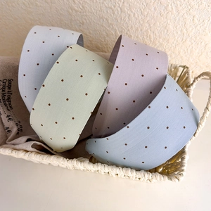 Detailed top view of four wide polka dot headbands in pastel colors inside a woven basket
