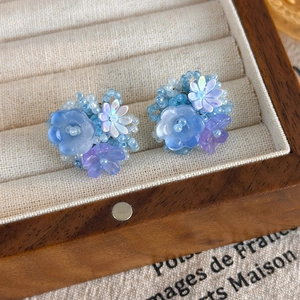 Détail macro de boucles d'oreilles fleuries faites à la main dans un écrin vintage