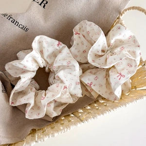 Floral print scrunchies set with pink blossoms and red bows on soft cream fabric