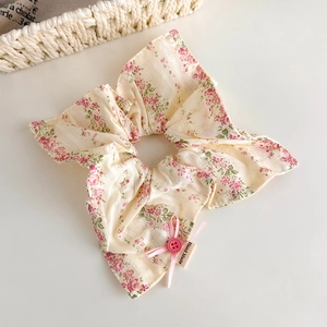 Chouchou floral avec nœud rose et bouton fait main sur une surface blanche propre
