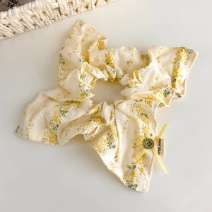 Détail du chouchou floral avec nœud jaune, bouton vert vintage et étiquette Hand Made