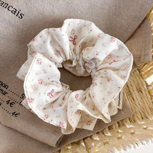 Detailed macro view of white floral scrunchie with pink flowers and handmade woven label