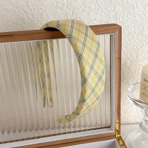 Detail of a vintage yellow plaid headband on a wooden box with warm ambient lighting