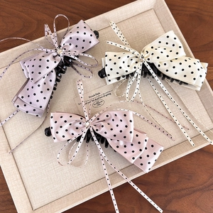 Close-up of three satin bow banana clips with polka dots and sparkling rhinestone center