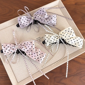 Three silk polka dot bow hair claws with long ribbons and crystals on a display tray