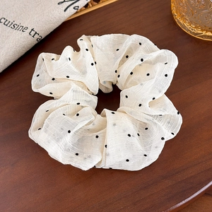French style cream scrunchie with black polka dots on a dark wood surface