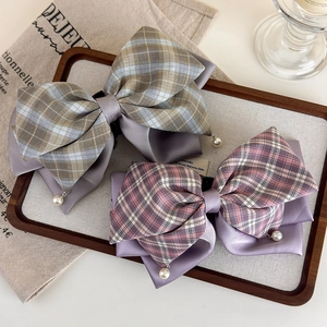 Détail de pinces à cheveux à nœuds à carreaux gris et violets avec perles et clip