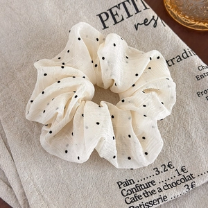 Detail shot of a French retro polka dot scrunchie on cream linen background fabric