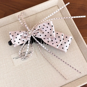 Detail of pink polka dot satin bow clip with a crystal center and long flowing ribbons