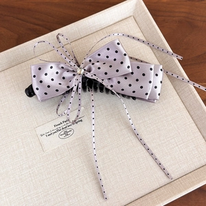 Close-up of purple polka dot ribbon bow hair clip with rhinestone and long streamers