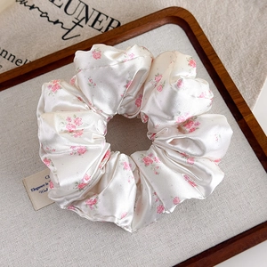 Dettaglio dell'elastico in raso francese con piccoli fiori rosa su tessuto crema