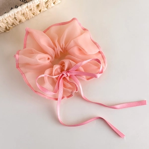 Detail of pink organza scrunchie with soft ribbon bow on a minimal background
