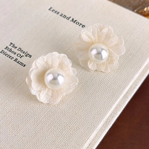 Detailed macro of fabric petal earrings with central pearl on vintage book background