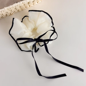 Detail of white organza scrunchie with black trim and long satin ribbon bow tie