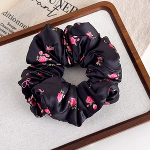 Dettaglio del grande elastico in raso nero con motivi floreali di rose rosa e fiocchi