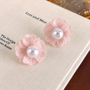 Close-up of pink lace flower earrings with a large white pearl center on a book