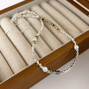 Collier de perles rétro avec pierres vertes et accents argentés dans un écrin