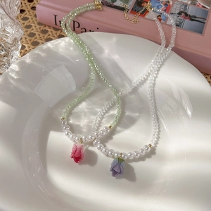 Dettaglio di eleganti collane con pendente a tulipano con perle e cristalli in un piatto