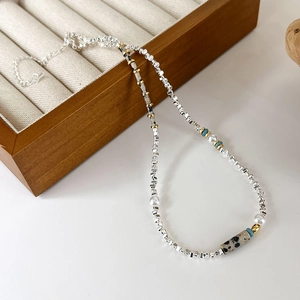 Détail du collier de perles avec billes en métal argenté et pierres turquoises