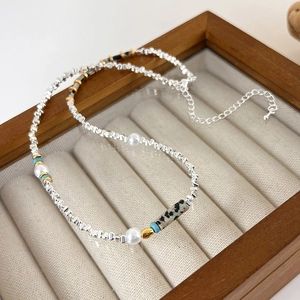 Détail de perles argentées et pierre verte sur un plateau à bijoux en velours