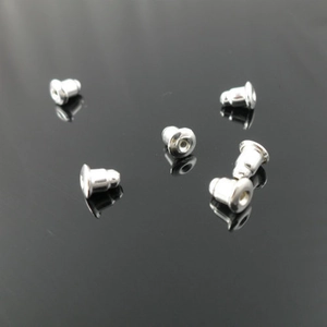 Macro view of six silver bullet-shaped metal earring backings on a black reflective surface