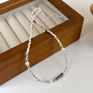 Détail d'un collier en perles argentées avec perles, touches de turquoise et pierre léopard