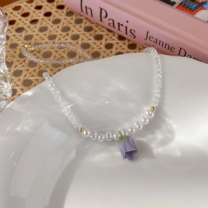 Dettaglio del ciondolo a tulipano viola su collana di perle e cristalli con decoro