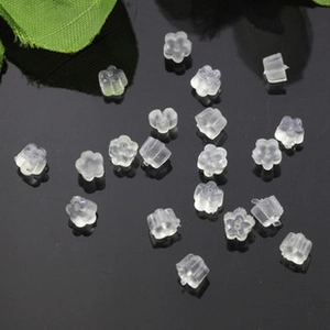 Top view of translucent flower-shaped silicone earring backs on a black reflective surface