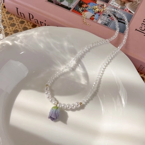 Dettaglio della collana tulipano con perle e cristallo viola su vassoio ceramica