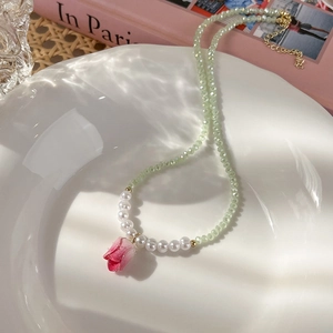 Dettaglio collana di perle con ciondolo a tulipano su vassoio in ceramica bianca