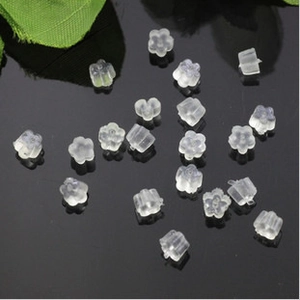 Flower shaped clear silicone earring back stoppers on a reflective black background