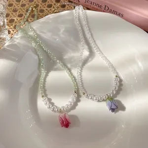 Eleganti collane di perle a tulipano con ciondoli floreali rosa e blu su un piatto di porcellana