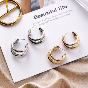 Detailed view of layered geometric C-shaped earrings in polished gold and silver finishes
